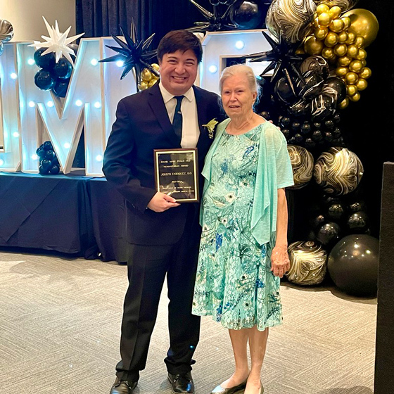 Joseph Enriquez stands with Dr. Pogue’s mother holding an award.